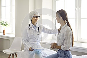 Smiling friendly female doctor touches patient& x27;s shoulder assuring that everything will be fine.