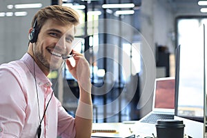 Smiling friendly handsome young male call centre operator.