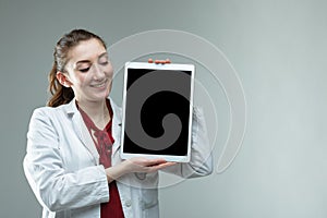 Smiling friendly woman doctor holding up a tablet