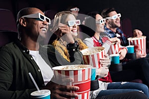 smiling friends in 3d glasses with popcorn and soda watching movie