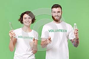 Smiling friends couple in volunteer t-shirt isolated on green background. Voluntary free work assistance help charity