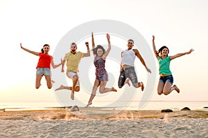 Smiling friends dancing and jumping on beach