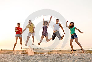 Smiling friends dancing and jumping on beach