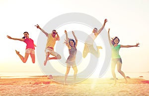 Smiling friends dancing and jumping on beach