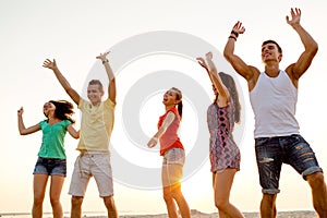 Smiling friends dancing on summer beach