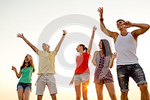 Smiling friends dancing on summer beach