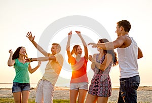 Smiling friends dancing on summer beach