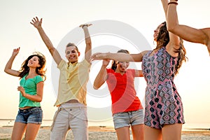 Smiling friends dancing on summer beach
