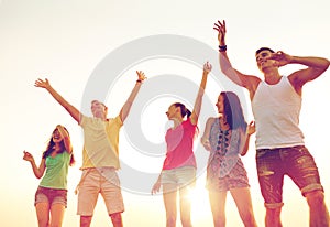 Smiling friends dancing on summer beach