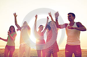 Smiling friends dancing on summer beach