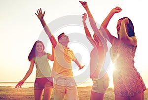 Smiling friends dancing on summer beach