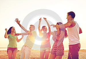 Smiling friends dancing on summer beach