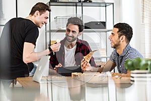 Smiling friends eating pizza and talking about digital cryptocurrency