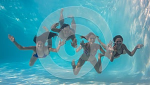 Smiling friends looking at camera underwater in swimming pool