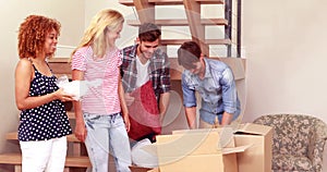 Smiling friends moving boxes together while saying goodbye