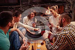 Smiling friends partying together and playing cards