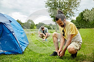 Smiling friends setting up tent outdoors