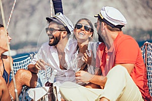 Smiling friends sitting on sailboat deck and having fun.