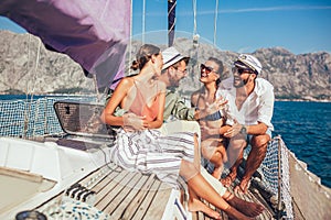 Smiling friends sitting on sailboat deck and having fun.