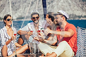 Smiling friends sitting on sailboat deck and having fun.