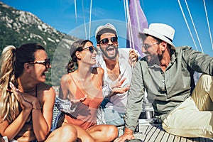 Smiling friends sitting on sailboat deck and having fun.