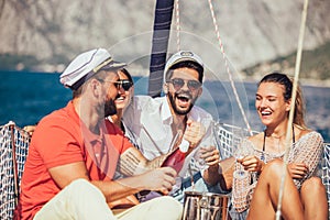 Smiling friends sitting on sailboat deck and having fun.