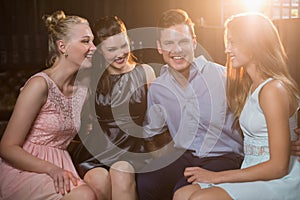 Smiling friends sitting together in sofa