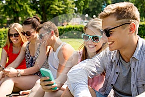 Smiling friends with smartphone making selfie