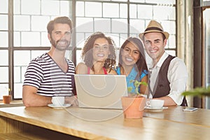 Smiling friends standing around laptop