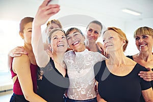 Smiling friends taking selfies together in a dance studio