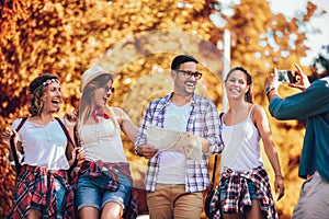 Smiling friends walking with backpacks in woods - adventure, travel, tourism, hike and people concept