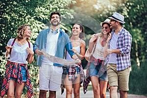 Smiling friends walking with backpacks in woods - adventure, travel, tourism, hike and people concept