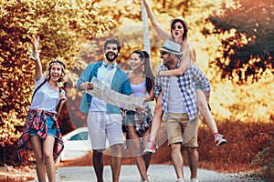 Smiling friends walking with backpacks in woods - adventure, travel, tourism, hike and people concept