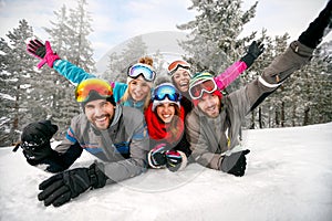 Smiling friends on winter holidays - Skiers lying on snow and ha