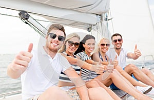 Smiling friends on yacht showing thumbs up