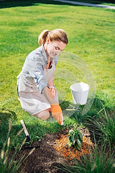 Smiling gardener enriching the soil after planting flowers in garden bed