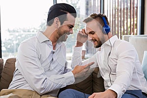 Smiling gay couple relaxing in living room