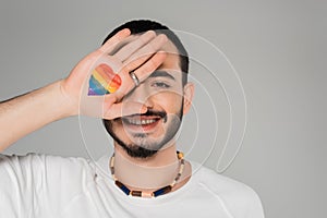 Smiling gay man covering eye with