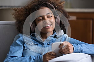 Smiling gen Z teen Black girl wearing big wireless headphones