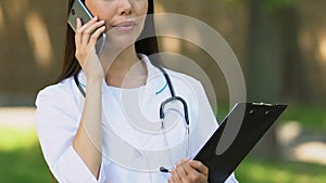 Smiling general practitioner talking phone with patient, informing about results