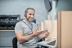 Smiling gesturing man in headphones near laptop