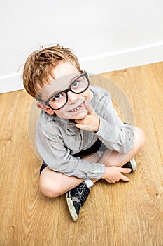 Smiling gifted boy with smart eyeglasses and tooth missing seated