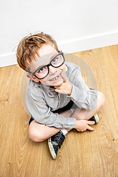 Smiling gifted boy with smart eyeglasses and tooth missing seated photo