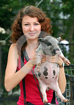 Smiling ginger girl holding piglet