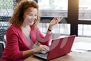 Smiling ginger woman talking per skype photo