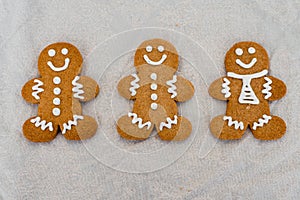 Smiling gingerbread man with sugar, spices, and vintage rolling pin on rustic, textile linen background.
