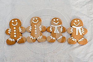 Smiling gingerbread man with sugar, spices, and vintage rolling pin on rustic, textile linen background.