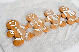 Smiling gingerbread man with sugar, spices, and vintage rolling pin on rustic, textile linen background.