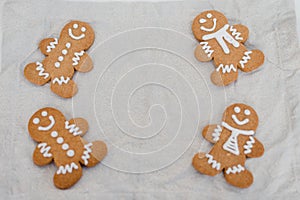 Smiling gingerbread man with sugar, spices, and vintage rolling pin on rustic, textile linen background.