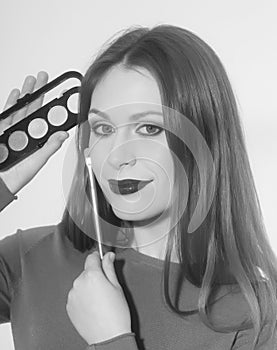 Smiling girl applying makeup on pretty face with brush